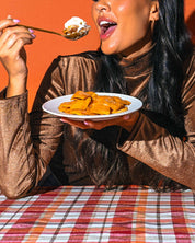 Woman smiles, enjoying Apple Pie Chewy Mango Bites with whipped cream.